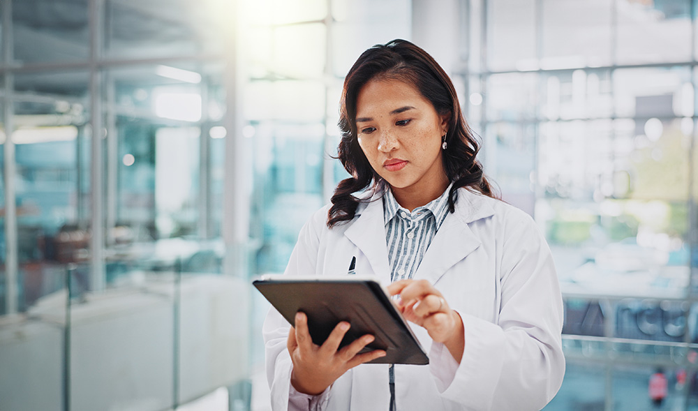 Female doctor in scrubs looking at a tablet