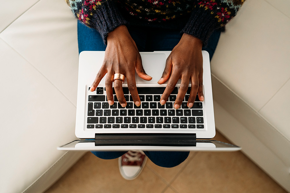 a person sitting on a couch using a laptop writing about an SEO copywriting service