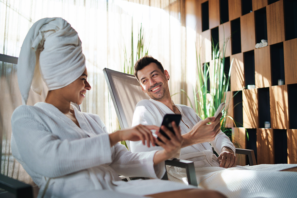 A couple at a spa using their phone to see what medspa hashtags to add to their social media post